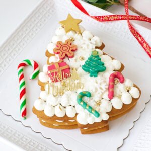 Postre navideño de galleta de miel con crema y frutas, presentado con decoraciones de Navidad.